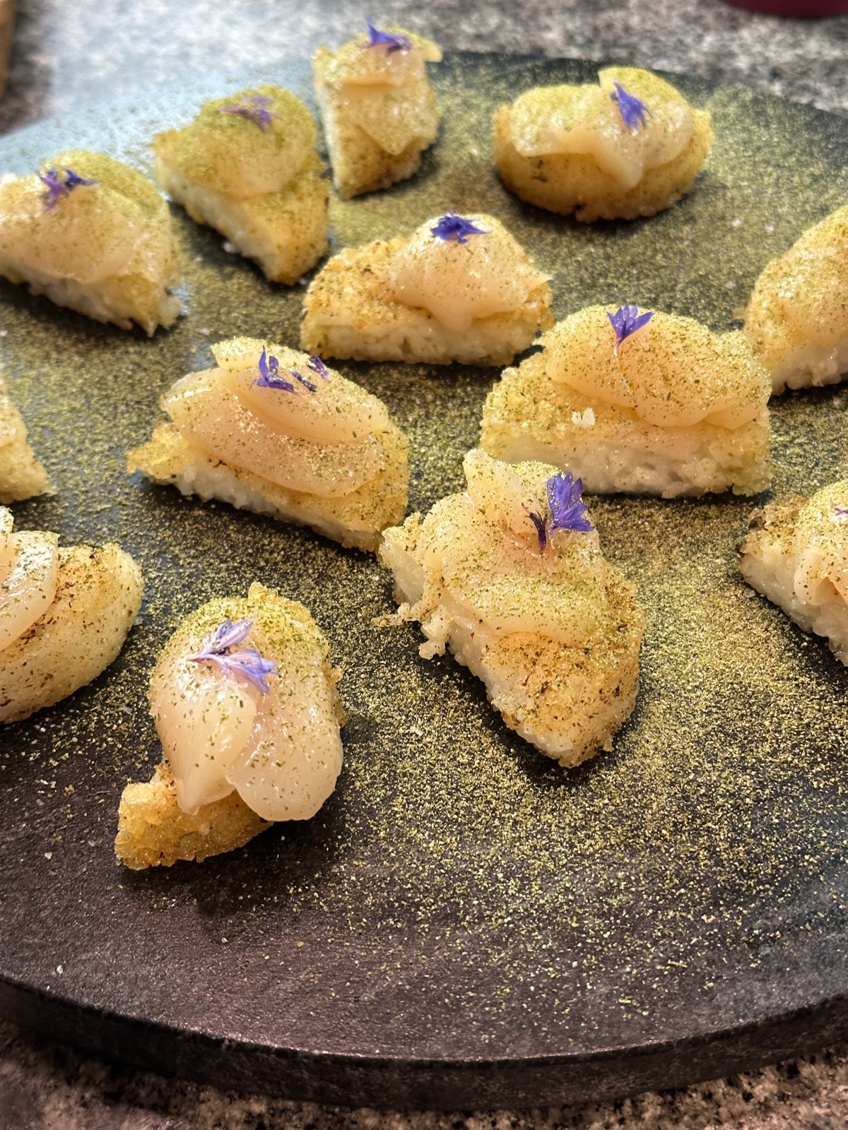 Crispy rice bites topped with scallop and edible flowers